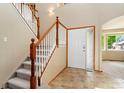 Inviting foyer featuring tiled flooring, a staircase with wooden banisters, and a front door with decorative glass at 11335 W 54Th Ln, Arvada, CO 80002