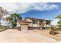 Well-maintained home with a spacious driveway and attached garage, surrounded by lush greenery at 261 Linda Ln, Denver, CO 80221