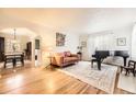 Bright living room featuring hardwood floors, a baby grand piano, and a comfortable seating area with floral artwork at 944 S Euclid Way, Denver, CO 80209