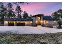 Brick home with a three-car garage and a long driveway, set against a backdrop of trees at 6517 Perry Park Blvd, Larkspur, CO 80118