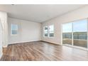 Spacious living room featuring hardwood floors, large windows, and a sliding glass door to the backyard at 19018 E 94Th Pl, Commerce City, CO 80022