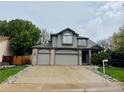 Two-story home with a three-car garage, gray siding, and well-maintained landscaping at 6002 Alkire Ct, Arvada, CO 80004