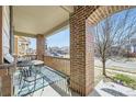 Charming front porch has bistro set and brick columns and a view of the street at 5177 Delphinium Cir, Brighton, CO 80601