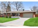 Inviting brick home with a lush green lawn and a spacious driveway leading to an attached garage at 3560 S Glencoe St, Denver, CO 80237