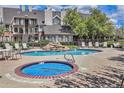 Community pool featuring a hot tub, comfortable lounge chairs, and mature trees for shade at 13762 E Lehigh Ave # G, Aurora, CO 80014