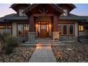 Inviting front porch with stone supports, wood accents, and beautiful landscaping with stone walkway at 8912 Little Raven Trl, Niwot, CO 80503