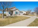 Lovely home with front porch, lush lawn, an attached garage and mature trees on the property at 19302 E 58Th Pl, Aurora, CO 80019