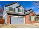 Two-story home with blue siding and brick accents, featuring a large garage and paved driveway at 1022 Morning Dove Dr, Longmont, CO 80504