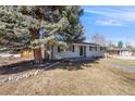 Front exterior showcases the home's facade with mature trees and a well manicured lawn at 495 S Olive Way, Denver, CO 80224