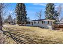 This single-story home has a large front yard and mature trees providing shade and curb appeal at 495 S Olive Way, Denver, CO 80224