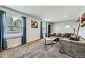 Bright living room features two large windows, cozy gray sectional sofa, and soft carpet at 10541 Routt St, Westminster, CO 80021