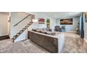 Cozy living room featuring carpet floors, a comfortable gray couch, and a staircase at 10541 Routt St, Westminster, CO 80021