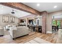 Open-concept living area featuring exposed brick, wood floors, and seamless flow to the kitchen at 4218 S Alton St, Greenwood Village, CO 80111