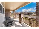 Charming covered front porch featuring brick columns, seating area, and view of the neighborhood at 5289 W Euclid Pl, Littleton, CO 80123