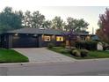 Charming single-story home with dark exterior, lush landscaping, and a two-car garage at 621 S Harrison Ln, Denver, CO 80209
