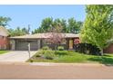 Inviting single-story home with well-manicured lawn, mature trees, and convenient driveway leading to the attached garage at 621 S Harrison Ln, Denver, CO 80209
