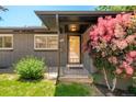 Close-up of a home's entrance, highlighting a small porch, door, and colorful mature flowering bushes at 621 S Harrison Ln, Denver, CO 80209