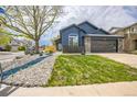 Inviting blue home with a stone-accented garage, lush lawn, and decorative landscaping at 12133 Crabapple St, Broomfield, CO 80020