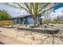 Charming blue home with lovely stone landscaping, green grass, and mature tree at 12133 Crabapple St, Broomfield, CO 80020
