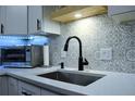 Close-up of kitchen sink featuring a modern faucet and patterned backsplash at 650 S Clinton St # 2A, Denver, CO 80247