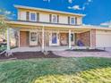 Inviting front facade with brick, porch seating, mature trees, and lush green lawn at 3790 E Geddes Ave, Centennial, CO 80122