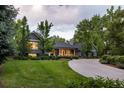 Beautiful home with lush landscaping and a winding driveway, surrounded by mature trees and green grass at 15 South Ln, Cherry Hills Village, CO 80113