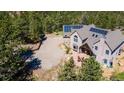 This aerial view showcases a beautiful home with solar panels and a large parking area nestled among lush green trees at 1057 Reed Ranch Rd, Boulder, CO 80302