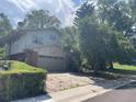 Traditional two-story home featuring a two-car garage with a basketball hoop and mature shade trees at 12682 W Louisiana Ave, Lakewood, CO 80228