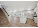 Open-concept living area featuring an island kitchen, stairs, wood floors, and plenty of natural light at 1318 Sienna Peak Cir, Erie, CO 80516