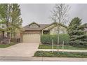 Lovely home with stone accents, dormer window, well-maintained landscaping, and a driveway leading to an attached garage at 17484 E 99Th Ave, Commerce City, CO 80022