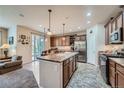 Open-concept kitchen with an island, seamlessly flowing to the dining area and outdoor access at 17484 E 99Th Ave, Commerce City, CO 80022