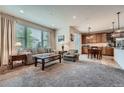 Bright living room with plush carpet, large windows, and an open floor plan leading to the dining and kitchen areas at 17484 E 99Th Ave, Commerce City, CO 80022