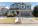 Two-story house with gray siding, stone accents, and a two-car garage at 15008 Clayton St, Thornton, CO 80602