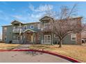 Two-story condo featuring balconies, brick accents, and a manicured lawn at 5335 Pecos Way # 4, Denver, CO 80221