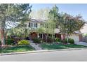 Traditional two-story home with well-maintained lawn and mature trees on a sunny day at 10886 E Berry Ave, Englewood, CO 80111