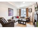 Comfortable living room featuring a large gray sectional couch, accent pillows, and a dark wood coffee table at 3449 W 63Rd Pl, Denver, CO 80221