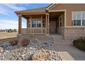 Close up of the home's front porch, with stone landscaping, brick veneer and a covered porch with seating at 21753 E Heritage Pkwy, Aurora, CO 80016