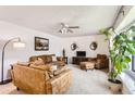 Bright living room with plush leather furniture, a ceiling fan, and large windows providing natural light at 2310 Squires Ct, Longmont, CO 80501