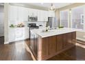 Modern kitchen with white cabinets, stainless steel appliances, large center island, and stylish pendant lighting at 9236 E 52Nd Dr, Denver, CO 80238