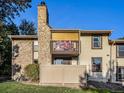 Rear view of the property showing stone exterior, balcony, and fenced yard at 7870 W 87Th Dr # L, Arvada, CO 80005