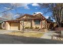 Tan home features an attached two-car garage, manicured front yard, and a brick retaining wall with a red trim at 3333 E Florida Ave # 108, Denver, CO 80210