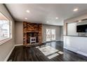 Bright living room features a brick fireplace, dark hardwood floors, and sliding glass doors at 229 Bross St # D, Longmont, CO 80501