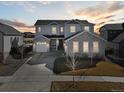 Beautiful two-story home with stone accents, three-car garage, and a well-manicured front yard at sunset at 1180 Ascent Trail Cir, Erie, CO 80516