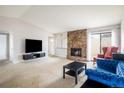 Cozy living room with a stone fireplace, plush seating, and sliding glass doors for natural light at 1321 Madero St, Broomfield, CO 80020