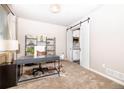 Cozy office with modern decor, natural light, and a sliding barn door leading to the kitchen at 605 Wild Honey Dr, Berthoud, CO 80513