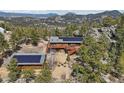 Gorgeous aerial view of a wood home, guesthouse, trees, fire pit, and boulders nestled amongst scenic mountain views at 31911 Warrens Rd, Golden, CO 80403