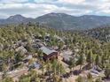 Expansive aerial view of the home, guesthouse, and scenic mountain views surrounded by towering trees and rock formations at 31911 Warrens Rd, Golden, CO 80403
