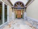 Inviting front entryway featuring a wooden door, stone pillars, and a meticulously designed arch at 1222 Buffalo Ridge Rd, Castle Pines, CO 80108