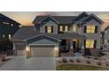 Beautiful two-story home with covered front porch during sunset with illuminated lighting at 8605 S Zante Ct, Aurora, CO 80016