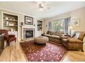 Cozy living room featuring a brick fireplace, built-in bookshelves, and plenty of natural light at 9625 S Hackberry St, Highlands Ranch, CO 80129